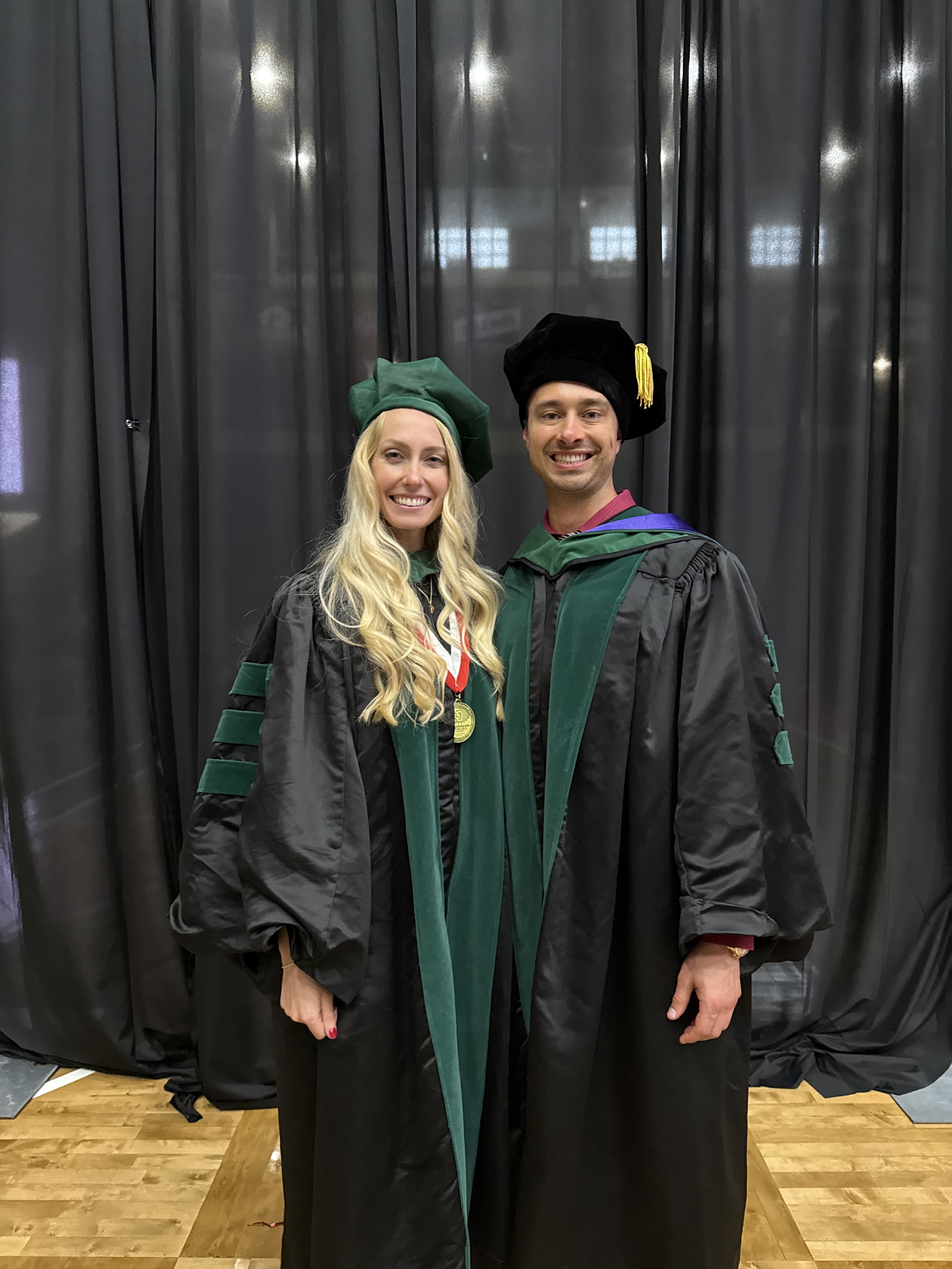 Dr. Alexander Reid with his sister Elise in graduation regalia at her medical school commencement